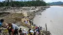 Kondisi ini memaksa warga mencari jalan seadanya untuk menyeberang sungai dengan aman. Tampak dalam foto, warga menyeberangi sungai di jembatan yang baru dibangun yang menghubungkan Aceh dan Provinsi Sumatera Utara setelah hancur akibat banjir bandang di Sungai Peusangan, Distrik Bireuen, Provinsi Aceh, Selasa 9 Desember 2025. (CHAIDEER MAHYUDDIN/AFP)