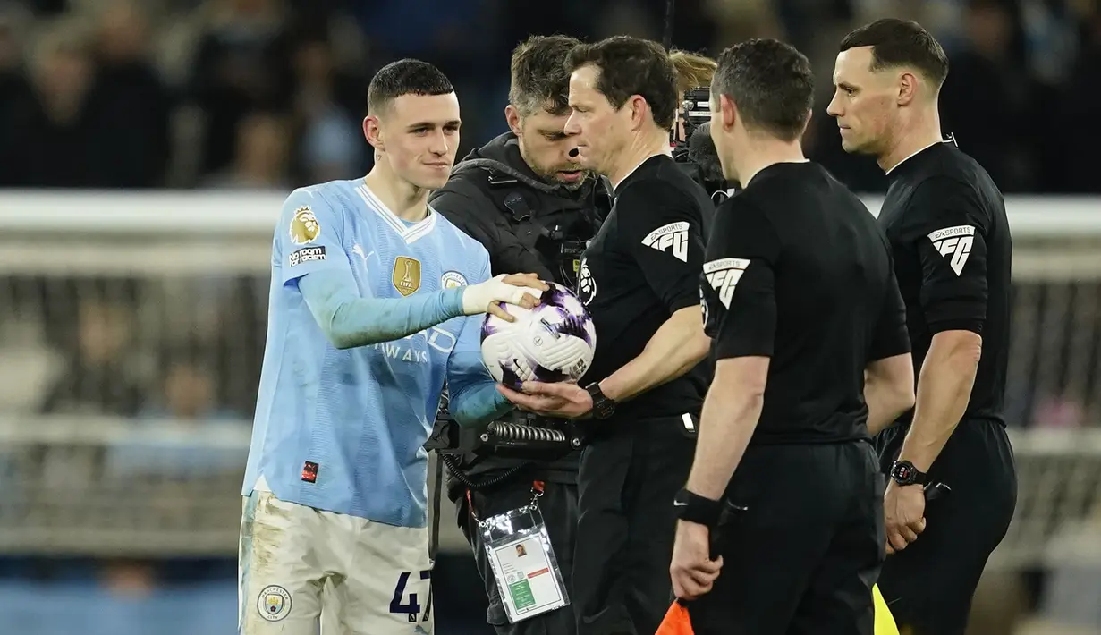 Gelandang Manchester City, Phil Foden yang sukses mencetak hattrick mengambil bola dari wasit setelah berakhirnya laga pekan ke-31 Premier League 2023/2024 menghadapi Aston Villa di Etihad Stadium, Manchester, Rabu (3/4/2024) malam. (AP Photo/Dave Thompson)