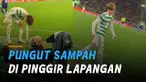 Seorang pemain bola memungut sampah yang berada di pinggir lapangan.