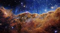 Gambar ini dirilis oleh NASA pada 12 Juli 2022, menunjukkan tepi daerah pembentuk bintang muda di dekatnya, NGC 3324 di Nebula Carina. Ditangkap dalam cahaya inframerah oleh Near-Infrared Camera (NIRCam) melalui Teleskop Luar Angkasa James Webb, gambar ini mengungkapkan area kelahiran bintang yang sebelumnya tak terlihat, menurut NASA. (NASA, ESA, CSA, and STScI via AP)