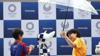 Seorang bocah berjabat tangan dengan robot maskot Olimpiade 2020, Miraitowa, pada acara hitung mundur setahun menjelang event tersebut, di Stadion Ajinomoto, Tokyo, Senin (22/7/2019). (AFP/Behrouz Mehri)