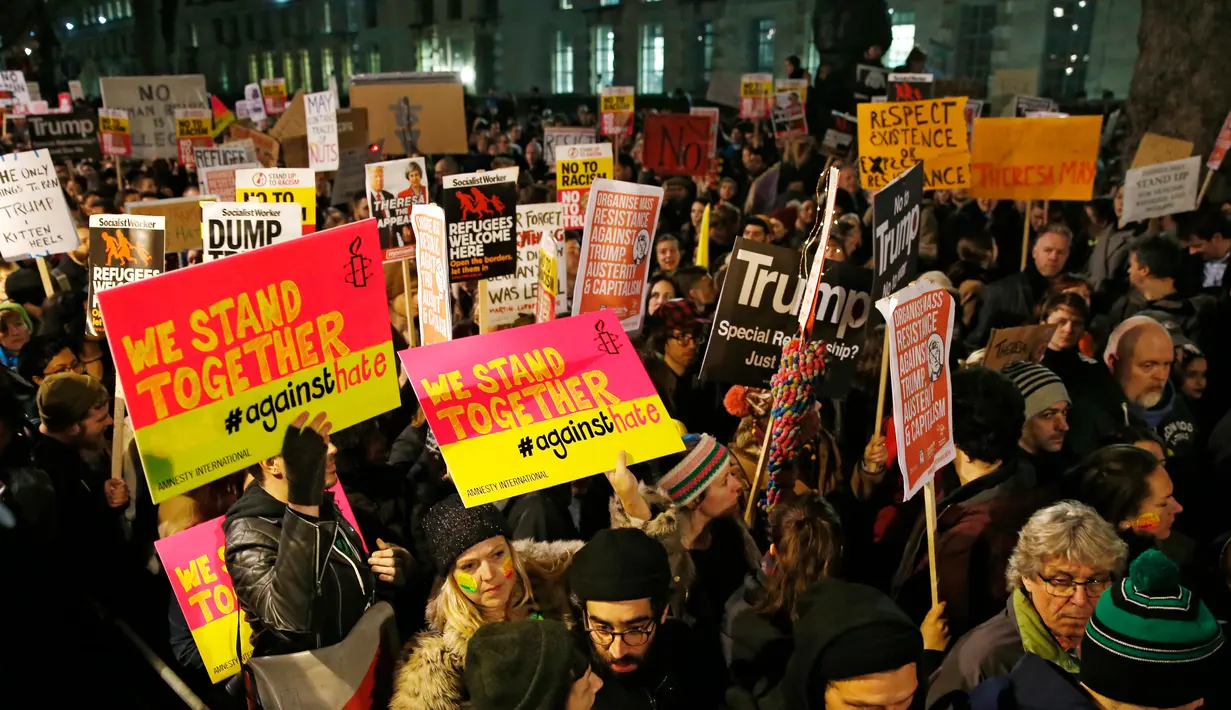 Sejumlah orang turun ke jalan, bergabung dalam aksi unjuk rasa di luar Downing Street, London, Senin (30/1). Mereka memprotes kebijakan Presiden AS Donald Trump yang melarang Muslim dari sejumlah negara memasuki Amerika Serikat. (AP Photo/Alastair Grant)