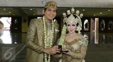 Lucky Hakim dan Tiara Dewi saat menunjukkan mahar dan cincin nikah seusai akad nikah di Masjid At Tin, Jakarta, Kamis (19/1/). Lucky Hakim dan Tiara Dewi melaksanakan akad nikah hari ini dengan mahar 500 gram logam mulia. (Liputan6.com/Herman Zakharia)