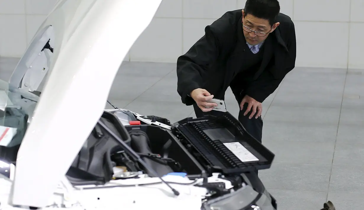 Pria mengambil gambar mesin mobil Honda S660 di Honda Motor Co di Tokyo, Jepang, (24/2). mobil sport mungil ini memiliki keunggulan dengan mengusung mesin kecil berkapasitas 660 cc turbo yang dikombinasikan penggerak roda depan. (REUTERS/Thomas Peter)