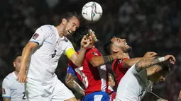 Pemain Uruguay Diego Godin (kiri) berebut bola udara dengan pemain Paraguay Gustavo Gomez (tengah) pada pertandingan sepak bola kualifikasi Piala Dunia 2022 di Stadion General Pablo Rojas, Asuncion, Paraguay, 27 Januari 2022. Uruguay menang 1-0. (AP Photo/Jorge Saenz)