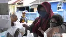Seorang ibu menggendong menerima nasi bungkus gratis di Kompleks Sinar Pamulang Permai, Pamulang Barat, Tangsel, Senin (13/4/2020). Nasi bungkus gratis ini bentuk kepedulian terhadap mereka yang berpenghasilan rendah dan terdampak perekonomiannya karena penyebaran Covid-19. (merdeka.com/Arie Basuki)
