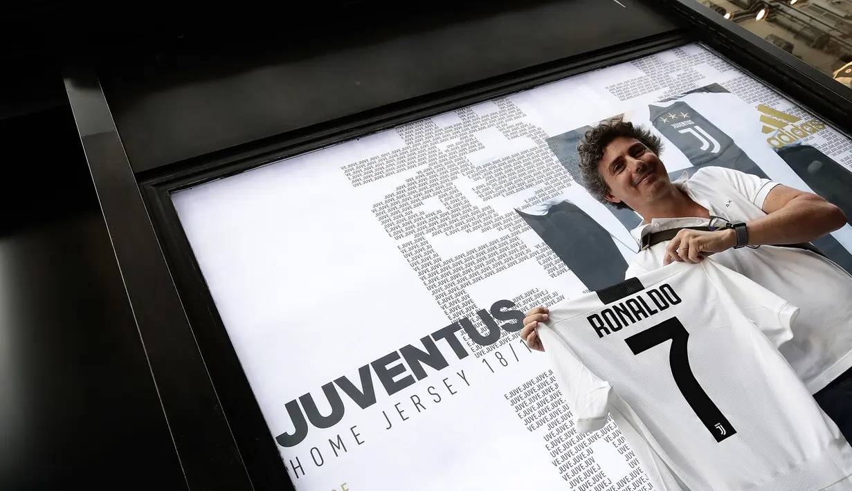 Seorang suporter memperlihatkan jersey Juventus atas nama Cristiano Ronaldo di depan toko resmi klub di Turin, Selasa (10/7). Ronaldo akan menerima gaji hingga 30 juta euro (Rp 504 miliar) per musim dari I Bianconeri. (AFP PHOTO / Isabella Bonottovv)