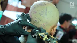 Seorang pengunjung saat ditato dibagian kepala dalam Event tato di Jakarta, Sabtu (23/9). Selain Lomba Tatto dalam acara tersebut ada juga pelatihan cara mentato yang benar dan rapih. (Liputan6.com/Helmi Afandi)