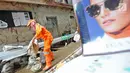 Petugas PPSU Kelurahan Kampung Melayu Siti Hajar membawa karung saat membersihkan sisa lumpur akibat banjir yang melanda Kebon Pala, Jakarta, Kamis (25/4). Siti Hajar (19) merupakan lulusan SMK (yang baru 4 bulan bekerja menjadi pasukan oranye. (Liputan6.com/Herman Zakharia)