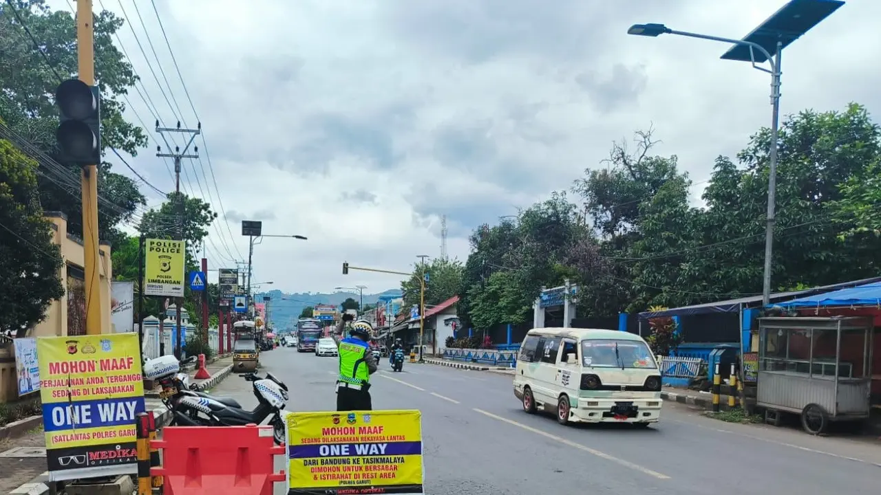 Salah satu anggota Polres Garut tengah memberikan peringatan bagi pemudik dalam sistem one way menjelang puncak arus balik lebaran Idul Fitri 1446H/2025 pada Sabtu (5/4/2025) petang. (Liputan6.com/Jayadi Supriadin)