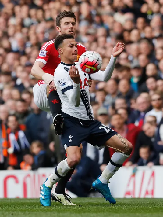 Gelandang Tottenham, Dele Alli (depan) mengontrol bola dengan dadanya dari kawalan gelandang MU, Michael Carrick pada lanjutan liga Inggris di stadion White Hart Lane, London, (10/4). Tottenham menang telak atas MU dengan skor 3-0. (Reuters/Eddie Keogh)