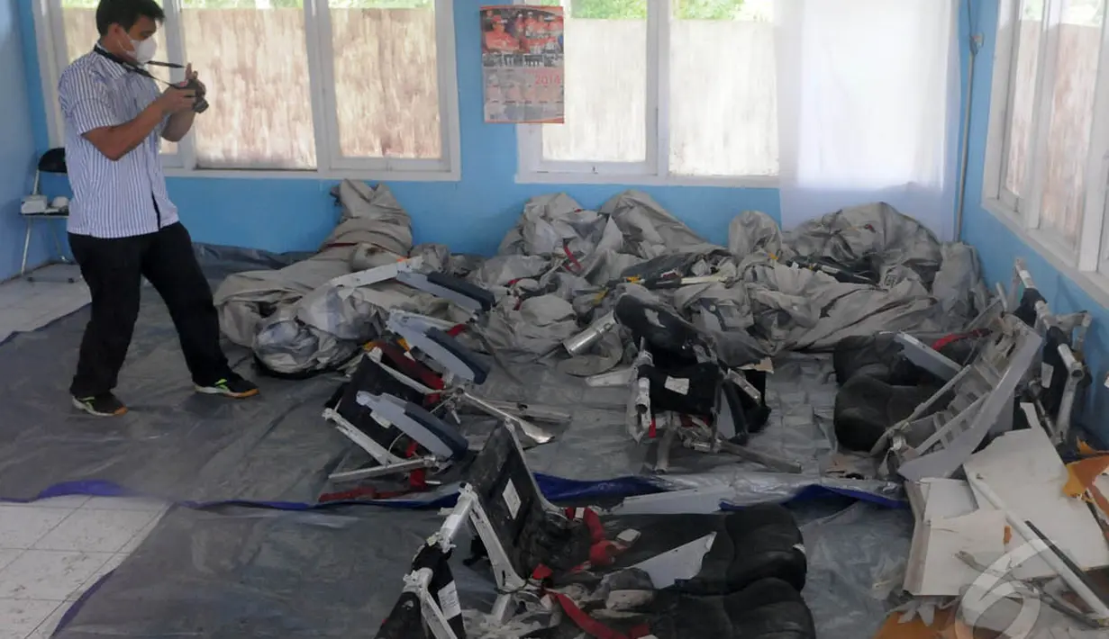 Seorang petugas terlihat mengambil gambar serpihan pesawat AirAsia QZ8501 di posko DVI Lanud TNI AU Iskandar, Pangkalan Bun, Selasa (6/1/15). (Liputan6.com/Herman Zakharia)