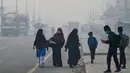Para siswa mengenakan masker saat mereka berjalan ke sekolah di tengah kabut asap pekat di Lahore, Pakistan pada 24 November 2023. (Arif ALI/AFP)