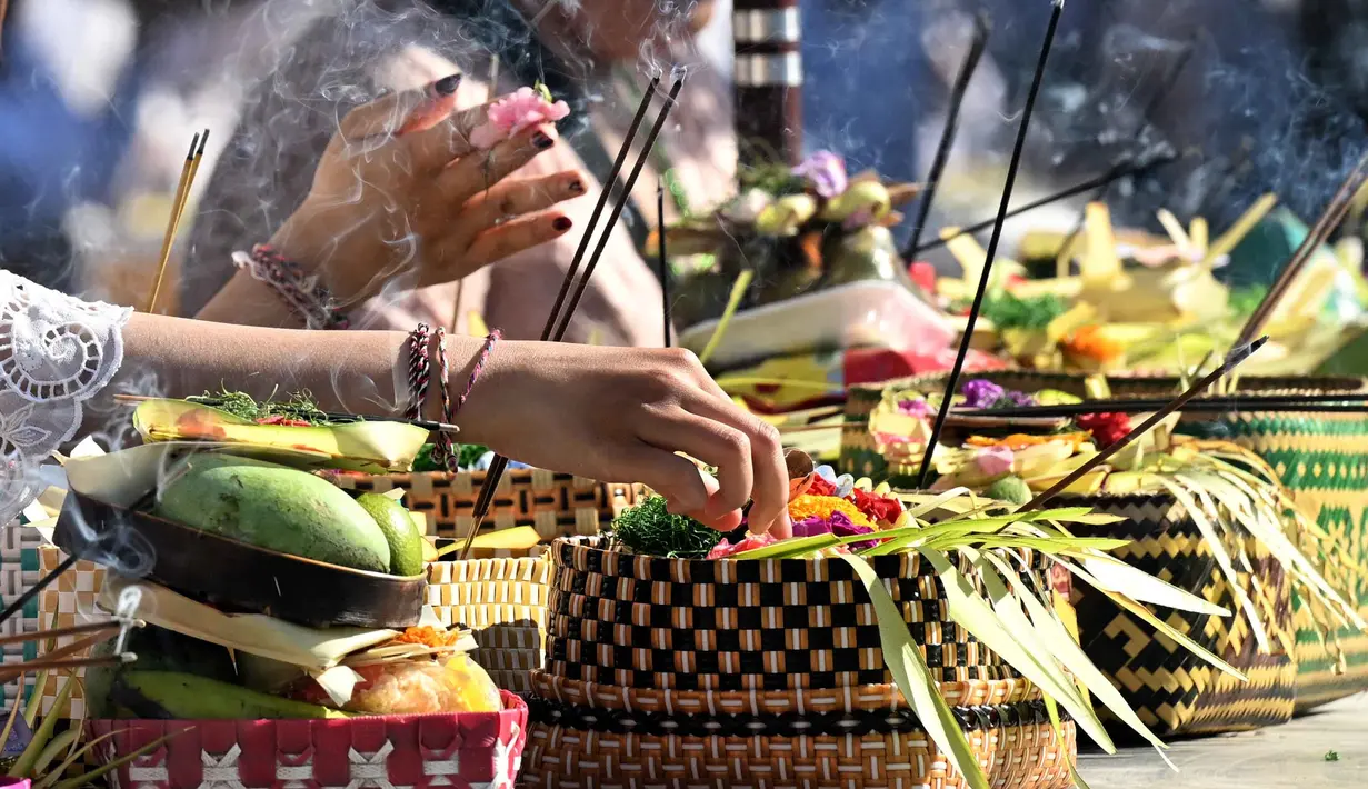 Umat Hindu meletakkan sesajinya di atas meja sebelum berdoa untuk merayakan Hari Raya Galungan di sebuah pura, Denpasar, Bali, Rabu 17 Juni 2026. (SONNY TUMBELAKA/AFP)