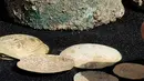 Sebuah bejana perunggu berisi koin emas kuno dan anting-anting ditemukan di sebuah situs penggalian di kota Mediterania Kaisarea, Israel, Senin (3/12). Koin-koin emas dalam bejana tersebut diperkirakan dibuat pada akhir abad ke-11. (JACK GUEZ/AFP)