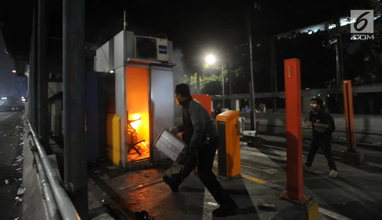 Petugas memadamkan api yang membakar gardu tol usai dibakar mahasiswa dalam demonstasi menolak pengesahan RUU KUHP dan revisi UU KPK di depan Gedung DPR/MPR, Jakarta, Selasa (24/9/2019). Hingga malam ini, mahasiswa masih berpencar di kawasan Senayan. (merdeka.com/Arie Basuki)