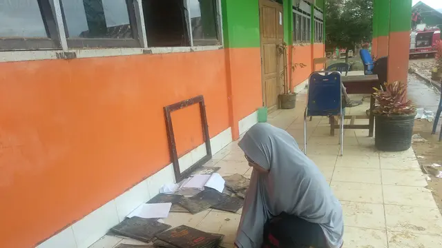 Kepala Sekolah S<PN 1 Andowia Konawe Utara, Suhepia (57)  memungut rapor siswa yang rusak terendam banjir.(Liputan6.com/Ahmad Akbar Fua)