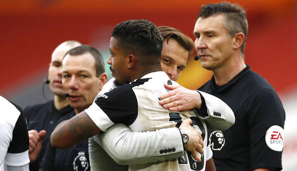 Pelatih Fulham, Scott Parker, memeluk Mario Lemina usai berhasil menaklukkan Liverpool pada laga Liga Inggris di Stadion Anfield, Minggu (7/3/2021). Fulham menang dengan skor 0-1. (Phil Noble/Pool via AP)