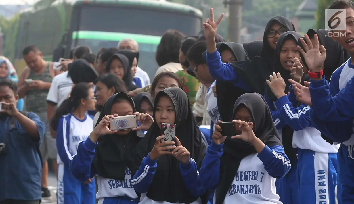 Sejumlah pelajar mengabadikan prosesi kirab kereta kencana pernikahan putri Presiden Jokowi,  Kahiyang Ayu-Bobby Nasution saat menuju Gedung Graha Saba di Surakarta, Rabu (8/11). (Liputan6.com/Angga Yuniar)