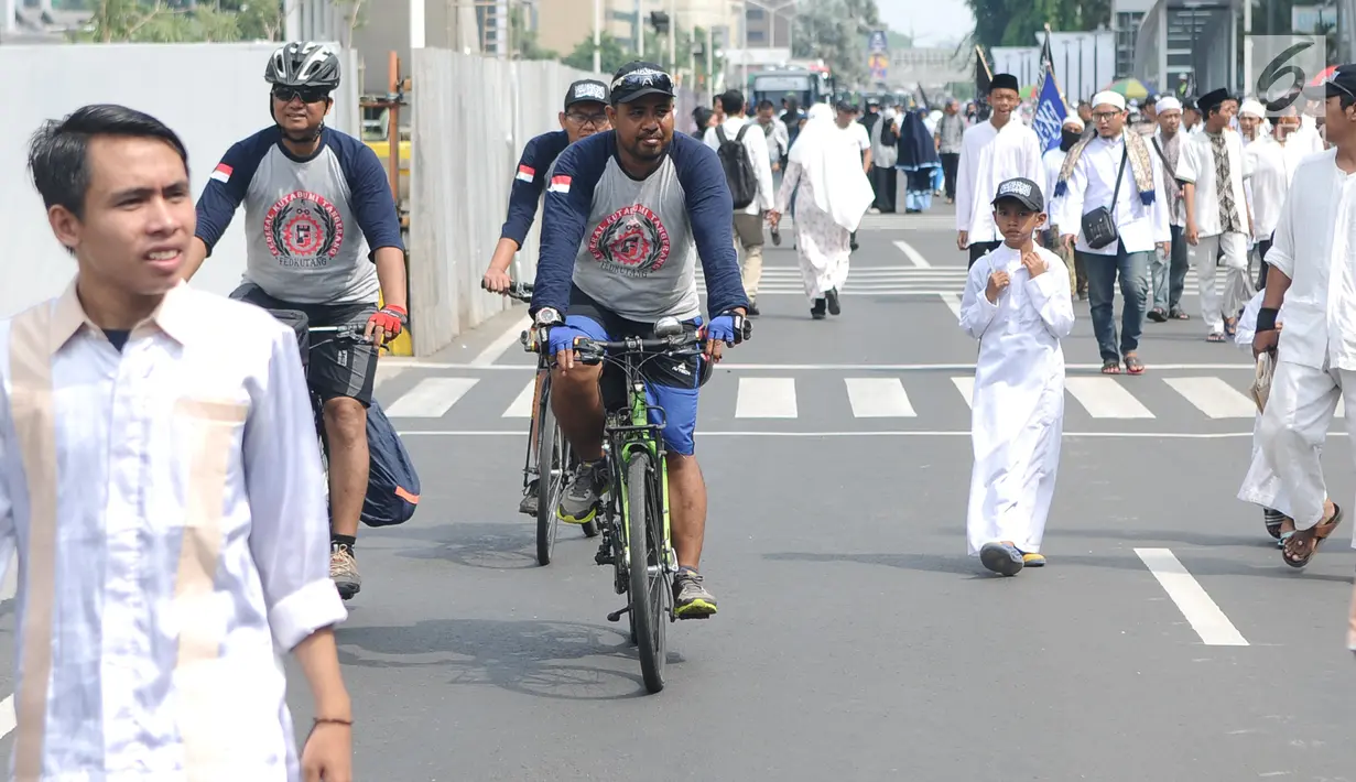 Sejumlah orang bersepeda di antara peserta Reuni 212 saat Car Free Day (CFD) di kawasan Jakarta, Minggu (2/12). Warga tetap memadati area Car Free Day  dari Bundaran HI-Sudirman meskipun ada aksi Reuni 212. (Liputan6.com/Angga Yuniar)