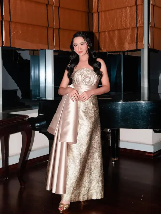 Masih dengan off-the-shoulder dress berwarna emas, Lyodra tampil menawan. Dress ini memiliki detail bentuk mawar di bagian dada, dengan kain panjang senada untuk siluet pita di bagian pinggang. Foto: Instagram.