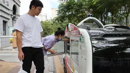 Orang-orang mengambil makanan dari sebuah kendaraan pengantar makanan otonomos usai membayar dengan memindai kode QR pada kendaraan itu di Taman Inovasi Huli di Xiamen, Provinsi Fujian, China, 6 November 2020. (Xinhua/Zeng Demeng)