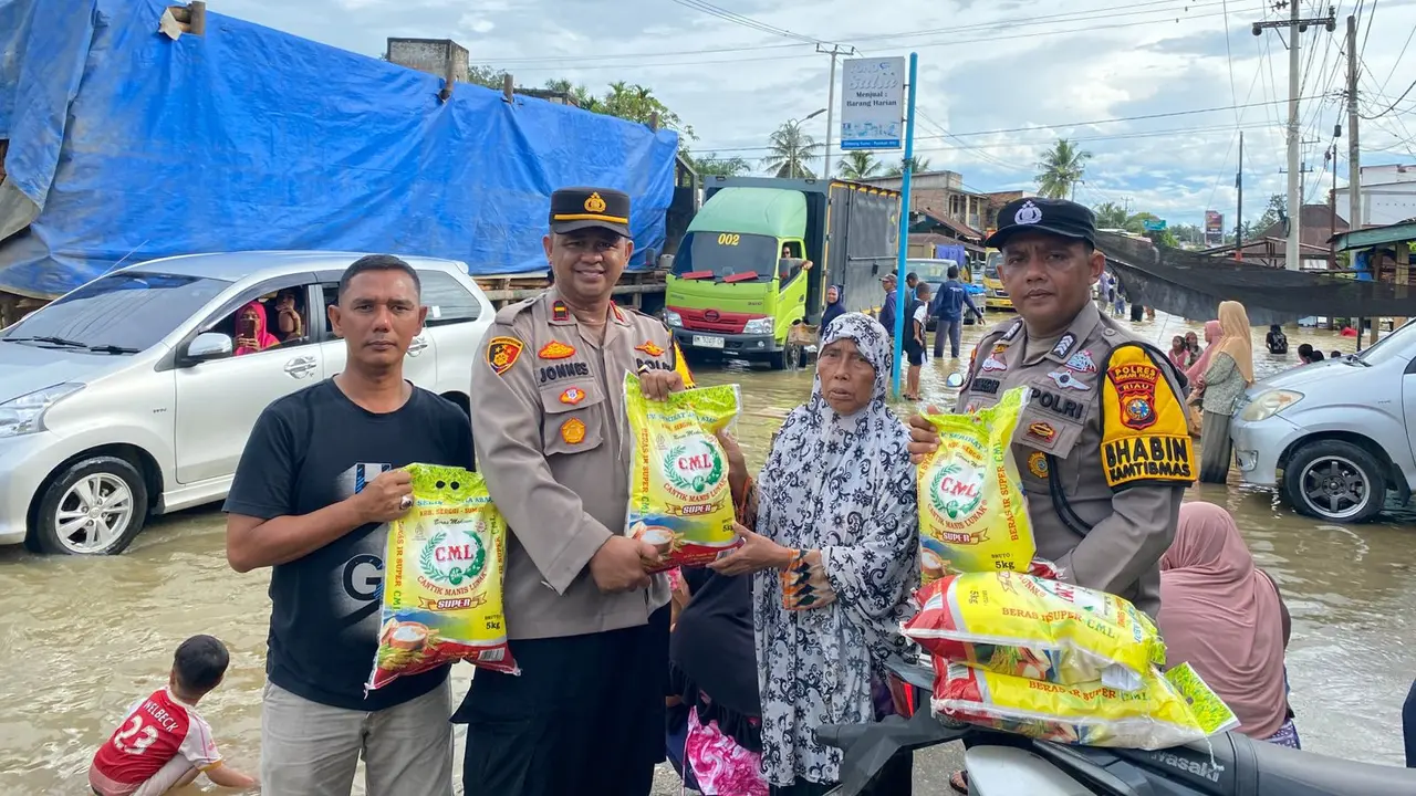 Personel Polres Rokan Hulu menyerahkan sembako kepada korban bencana banjir di Rambah Hilir.