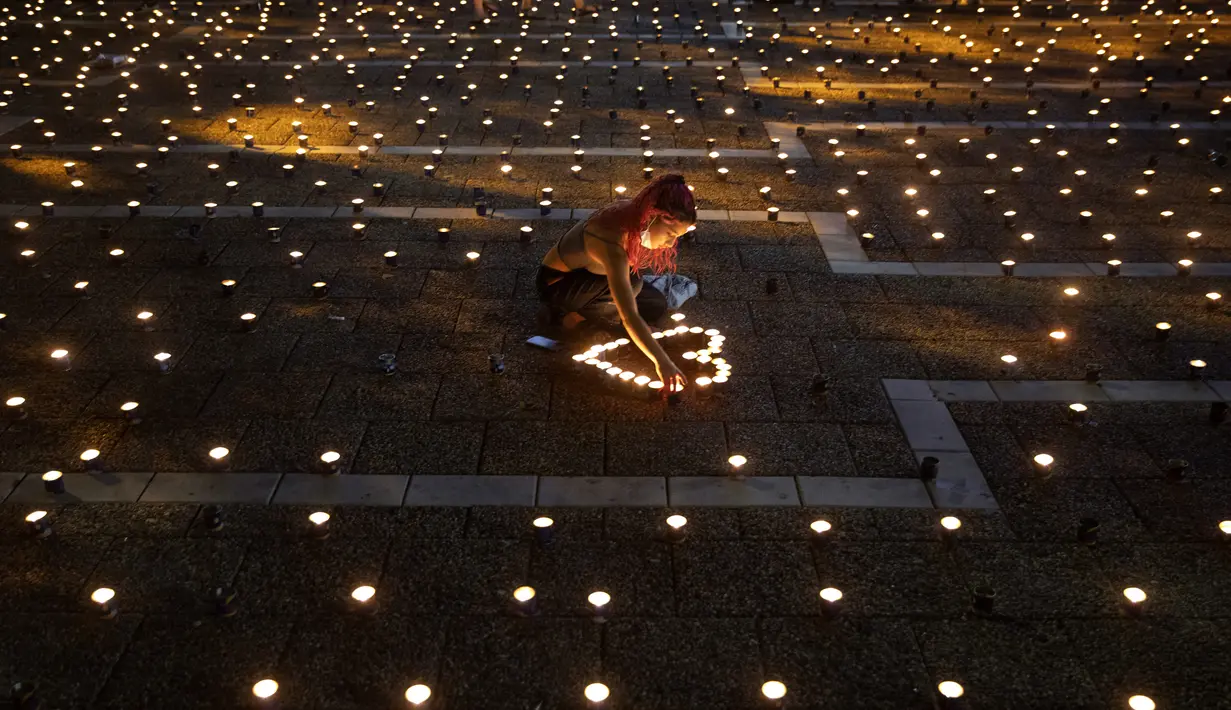 Seorang perempuan menyalakan lilin pada peringatan 25 tahun pembunuhan Perdana Menteri Israel Yitzhak Rabin, di Rabin Square, Tel Aviv, Kamis (29/10/2020). Sebanyak 25 ribu lilin dinyalakan oleh warga Israel untuk memperingati pembunuhan  Yitzhak Rabin. (AP Photo/Oded Balilty)
