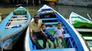 Warga berpose di atas sampan di Kampung Aquarium, Jakarta Utara, Senin (28/3). Warga mengaku resah terkait rencana Pemprov DKI Jakarta yang akan melakukan penertiban di kawasan Luar Batang, Penjaringan, Jakarta Utara. (Liputan6.com/Gempur M Surya)