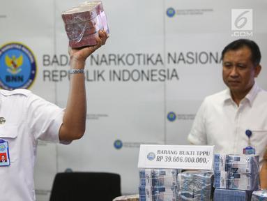 Kepala BNN Komjen Budi Waseso menunjukkan barang bukti hasil tindak pidana pencucian uang (TPPU) kasus narkoba di BNN, Jakarta, Selasa (13/6). BNN mengungkap kasus TPPU dengan total aset Rp 39 miliar dari kedua kasus berbeda. (Liputan6.com/Yoppy Renato)