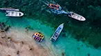 Pemandangan udara menunjukkan orang-orang saat berkumpul menikmati masa libur panjang Idulfitri di area olahraga air, Pantai Lhoknga, Aceh, pada Kamis 26 Maret 2026. Libur perayaan Idulfitri 1447 Hijriah memberi kesempatan panjang bagi warga Aceh untuk berwisata, salah satunya ke Pantai Lhoknga. (Chaideer MAHYUDDIN/AFP)