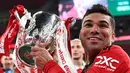 Gelandang Manchester United, Casemiro memegang trofi Carabao Cup 2022/2023 selama perayaan juara usai mengalahkan Newcastle United pada laga final di Stadion Wembley di London, Senin dini hari WIB (27/2/2023). Casemiro juga berperan besar membantu pertahanan dengan 5 tekel bersih dan 58% umpan sukses. (AFP/GLYN KIRK)