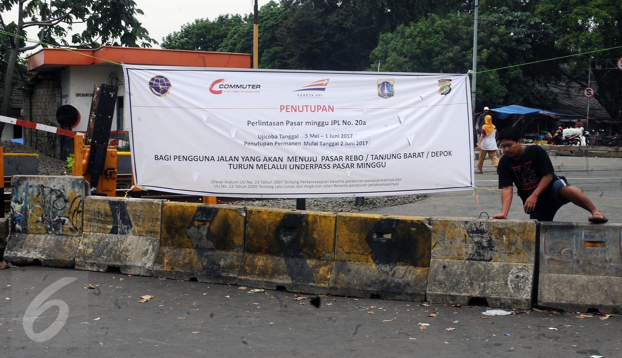 Warga melompati beton pembatas penutupan sementara perlintasan KRL Commuter Line sebidang di Pasar Minggu, Jakarta, Selasa (9/5). Penutupan secara permanen akan dilakukan pada 2 Juni mendatang. (Liputan6.com/Helmi Fithriansyah)