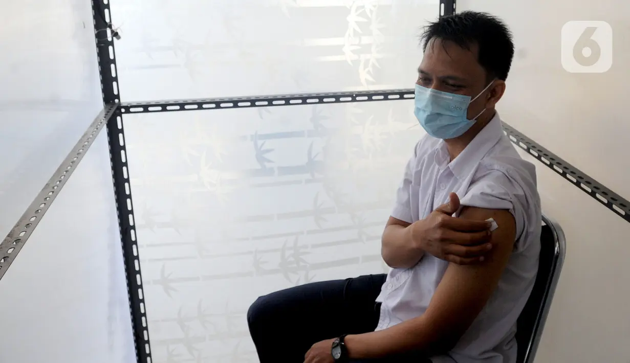 Seorang pria memegang lengannya usai disuntik vaksin virus corona COVID-19 produksi Sinovac saat kegiatan vaksinasi di Puskemas Jagakarsa, Jakarta Selatan, Kamis (14/1/2020). Sejumlah Puskesmas di Jabodetabek mulai melakukan vaksinasi COVID-19 pada hari ini. (merdeka.com/Arie Basuki)