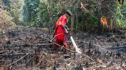 Pelajar bernama Rudiansyah dengan mengenakan kostum Superman membantu memadamkan kebakaran hutan dan lahan di Petuk Katimpun, Palangkaraya, Kalimantan Tengah, 17 Agustus 2026. (AFP/ Reina)