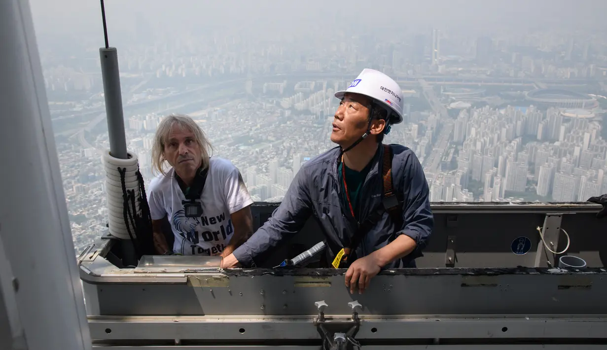 Urban climber atau pemanjat gedung, Alain Robert diamankan petugas saat memanjat Menara Lotte World di Seoul, Korea Selatan (6/6). (AFP/Ed Jones)