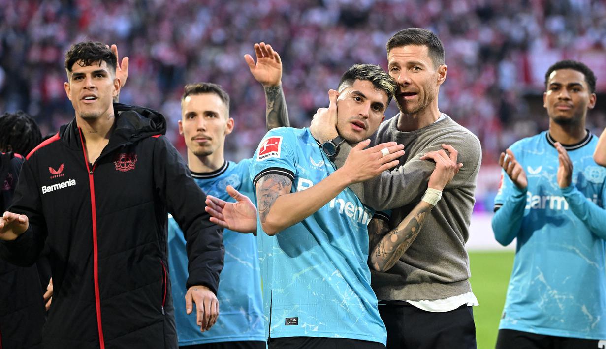 Pelatih Bayer Leverkusen, Xabi Alonso memeluk pemainnya Exequiel Palacios (tengah) setelah laga lanjutan Bundesliga melawan FC Cologne di Cologne, Jerman, 3 Maret 2024. (AFP/Ina Fassbender)
