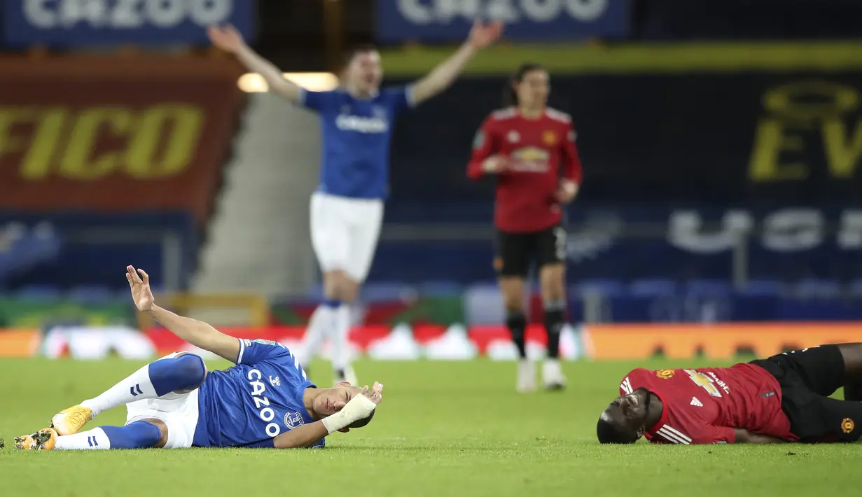 Striker Everton, Richarlison (kiri) dan bek Manchester United, Eric Bailly, tergeletak di lapangan usai terlibat benturan dalam laga perempatfinal Piala Liga Inggris Carabao Cup di Goodison park, Rabu (23/12/2020). Everton kalah 0-2 dari Manchester United. (AP/Nick Potts/Pool)