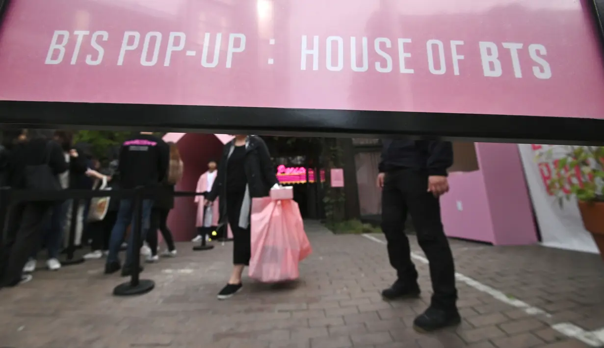 Penggemar membawa kantong plastik usai berbelanja dari toko pop-up BTS di Distrik Gangnam, Seoul, Korea Selatan, Jumat (18/10/2019). House of BTS akan dibuka hingga 5 Januari 2020 mendatang. (Jung Yeon-je/AFP)
