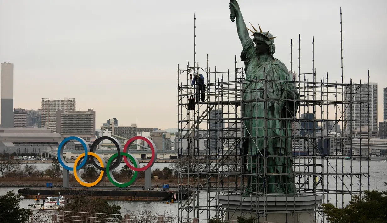 Pekerja memasang perancah pada replika Patung Liberty saat kapal tongkang membawa Cincin Olimpiade di Distrik Odaiba, Tokyo, Jepang, Jumat (17/1/2020). Cincin Olimpiade dengan tinggi 15,3 meter dan panjang 32,6 meter tersebut akan berada di sana hingga Olimpiade 2020 berakhir. (AP Photo/Jae C. Hong)