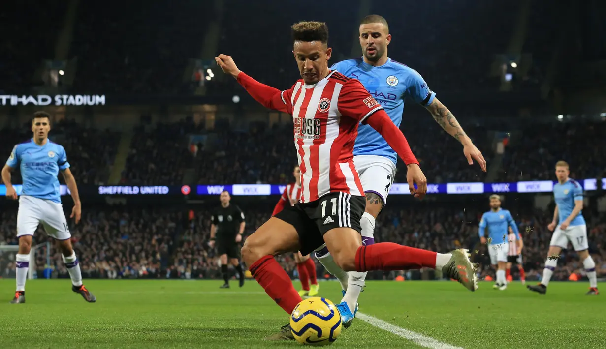 Striker Sheffield United, Callum Robinson berebut bola dengan bek Manchester City, Kyle Walker pada laga pekan ke-20 Liga Inggris di Etihad Stadium, Minggu (29/12/2019). Hasil manis dipetik Manchester City usai meraih kemenangan 2-0 saat menjamu Sheffield United. (Lindsey Parnaby / AFP)