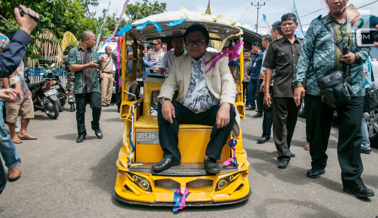 Ketua DPD RI, Oesman Sapta Odang menaiki becak motor (bentor) saat meninjau proyek padat karya di Desa Bilalang, Kota Kotamobagu, Sulawesi Utara, Kamis (12/4). Dalam kunjungan itu, OSO mendampingi Menteri Desa PDTT, Eko Putro Sandjojo. (Liputan6.com/Pool)