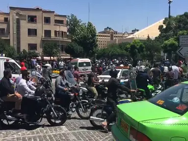 Sejumlah orang berkumpul di depan parlemen Iran di Teheran,  Rabu (7/6). Tiga pria bersenjata dilaporkan melakukan penyerangan di dalam gedung parlemen Iran dengan menggunakan senjata api. (AFP/ATTA KENARE)