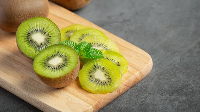 Buah kiwi utuh dan yang sudah dipotong di atas talenan (Foto Dok: Freepik/jcomp)