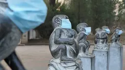 Masker terpasang pada mulut patung berbentuk monyet di Kebun Binatang Beijing, China sebagai bentuk protes, 19 Desember 2016. Kondisi asap yang semakin pekat membuat polusi udara di kota Beijing berada jauh diambang batas aman. (AFP PHOTO/STR/China OUT)