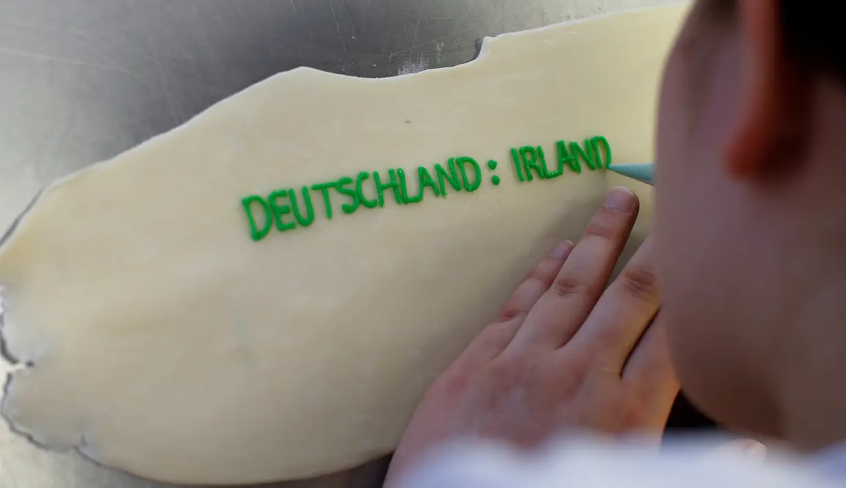 Pembuat kue menuliskan nama kontestan peserta Euro 2016 yang dibuat di sebuah tempat pembuatan kue di Munich, Jerman, Senin (20/6). Beraneka kue bertema Euro 2016 mewarnai perhelatan sepakbola Eropa. (REUTERS/Michaela Rehle)