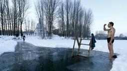 Seorang pria bersiap untuk mandi di dalam air es di danau dalam prosesi perayaan Epifani Ortodoks di Minsk, Belarusia (19/1/2016). Umat Kristen Ortodoks merayakan Epifani yang jatuh pada 19 Januari. (REUTERS/Vasily Fedosenko)