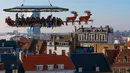 Para tamu menikmati makan malam di "Santa in the sky", yang diangkat dengan crane dan dihias menyerupai "Santa Sleigh" di Brussels, Belgia, 25 November 2016. Tempat ini didekorasi seperti kereta Santa Claus menjelang perayaan Natal. (REUTERS/Yves Herman)
