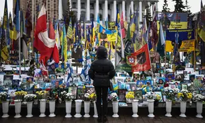 Seorang warga setempat berdiri di depan tugu peringatan sementara untuk tentara Ukraina di Lapangan Kemerdekaan, Kyiv, saat peringatan keempat invasi Rusia ke Ukraina, Selasa 24 Februari 2026. Hari ini, perang Rusia-Ukraina yang pecah pada 24 Februari 2022 telah berlangsung selama empat tahun. (HENRY NICHOLLS/AFP)