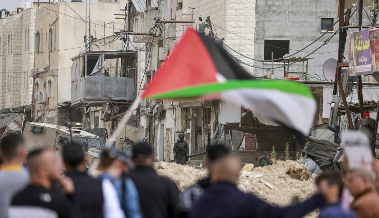 Sementara, militer Israel menetapkan kamp tersebut sebagai zona tertutup, yang melarang siapapun masuk atau keluar tanpa izin khusus. Tampak dalam foto, warga Palestina berunjuk rasa setelah tentara Israel memblokir pintu masuk kamp pengungsi Palestina Nur Shams di Tepi Barat yang diduduki pada Senin 9 Februari 2026. (Jaafar ASHTIYEH/AFP)